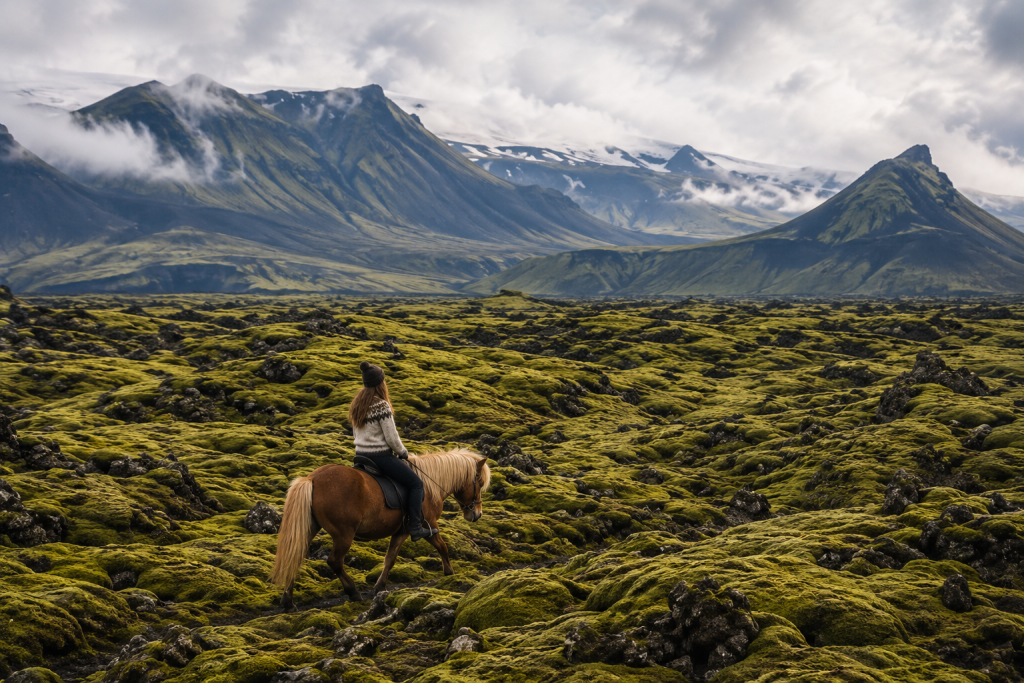 She Rode Into The Horizon And Never Fully Came Back. The Complete Guide To Horse Riding Travel For Women 3 πΈ Image: A Woman On A Small Icelandic Horse Crossing A Lava Field Covered In Green Moss, Mountains Behind Her. The Smallness Of The Horse Relative To The Landscape Creates The Feeling Of A Child'S Adventure Book Come To Life.